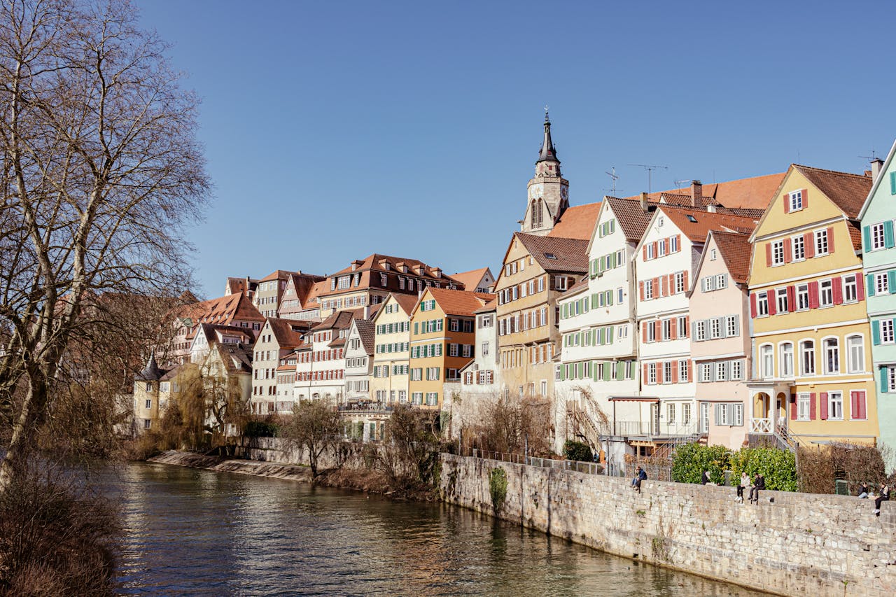 Picturesque view of historic colorful homes by the Neckar River in Tübingen, Germany, under a clear blue sky.
